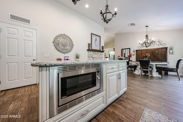 9085 E Windrose Dr, Scottsdale, AZ 85260 - kitchen with a chandelier, vaulted ceiling, stainless steel microwave, wood finished floors, and white cabinetry