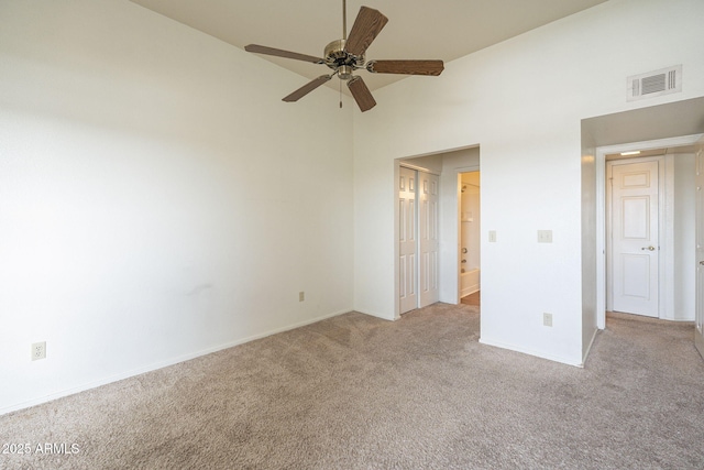 unfurnished bedroom featuring carpet floors, visible vents, a high ceiling, connected bathroom, and baseboards