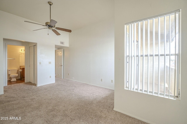 unfurnished bedroom with ensuite bathroom, high vaulted ceiling, carpet flooring, visible vents, and baseboards