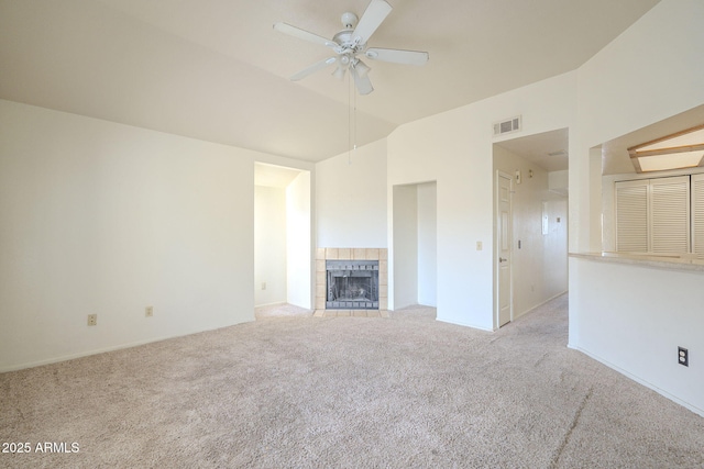 unfurnished living room featuring lofted ceiling, a tile fireplace, carpet floors, visible vents, and a ceiling fan