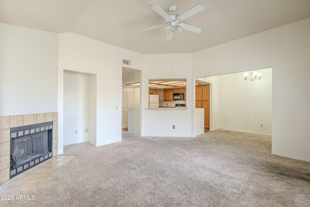 unfurnished living room with carpet, a fireplace, lofted ceiling, visible vents, and a ceiling fan