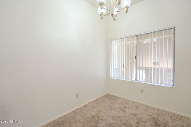 carpeted empty room featuring baseboards and a chandelier