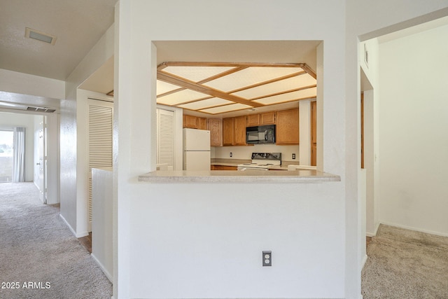 kitchen featuring black microwave, range with electric stovetop, freestanding refrigerator, and light colored carpet