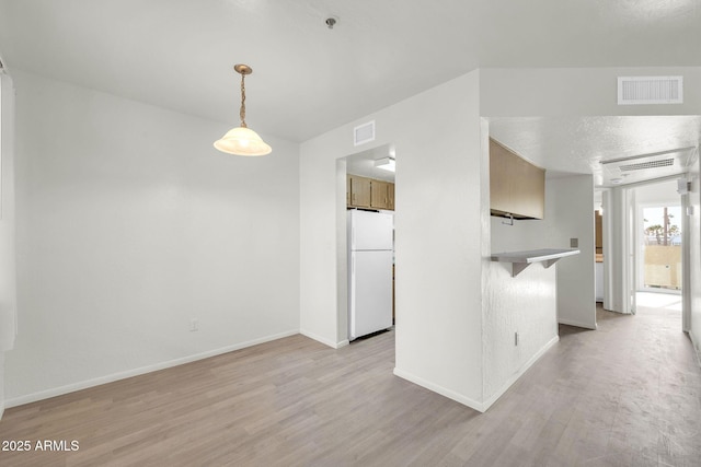 interior space with visible vents, baseboards, a textured ceiling, and light wood finished floors