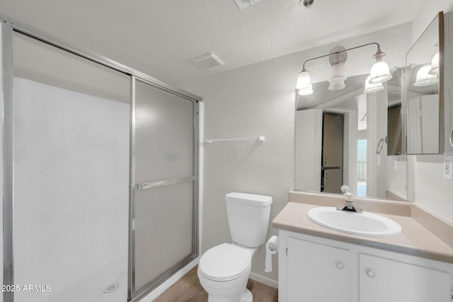 full bathroom featuring visible vents, toilet, a stall shower, a textured wall, and vanity