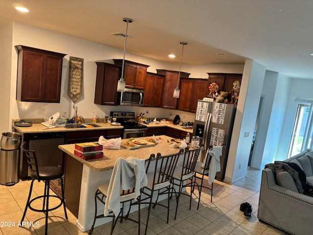 kitchen with a center island, light tile floors, a breakfast bar, decorative light fixtures, and stainless steel appliances