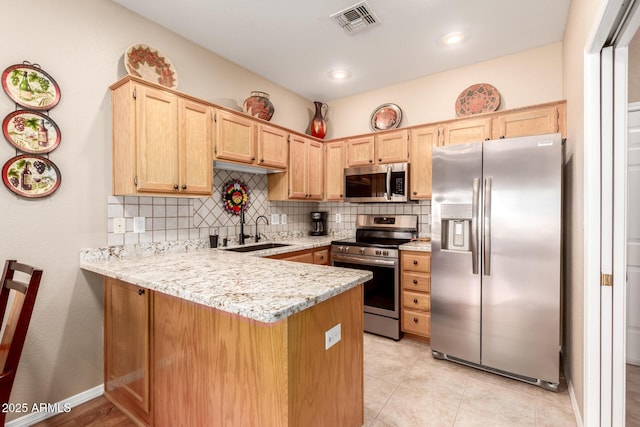 kitchen featuring light stone counters, kitchen peninsula, sink, and appliances with stainless steel finishes