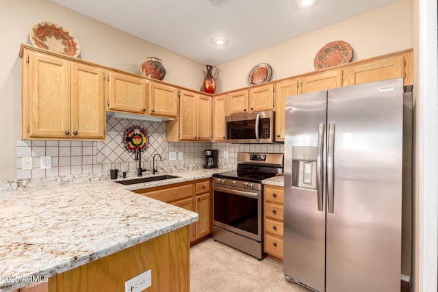 kitchen with sink, tasteful backsplash, light stone counters, light tile patterned flooring, and appliances with stainless steel finishes