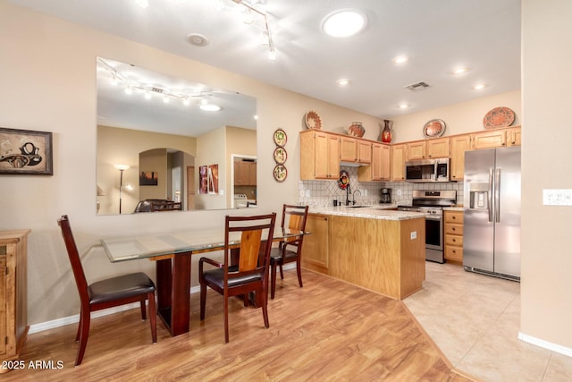 kitchen featuring sink, tasteful backsplash, light brown cabinetry, appliances with stainless steel finishes, and kitchen peninsula