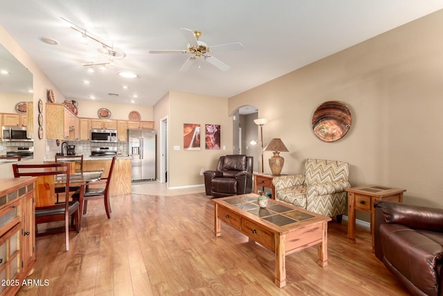 living room featuring ceiling fan, sink, and light wood-type flooring