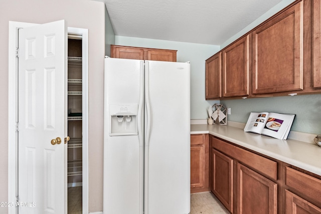 2327 E Meadow Creek Way, San Tan Valley, AZ 85140 - kitchen featuring white fridge with ice dispenser, brown cabinets, light countertops, and light tile patterned floors