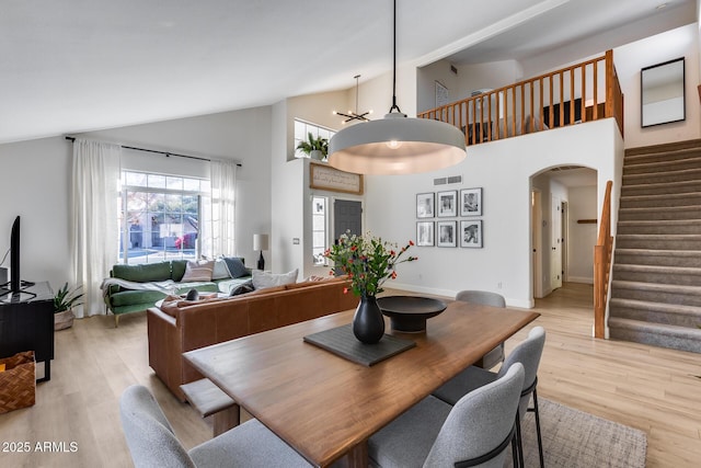 dining area with a chandelier, light hardwood / wood-style flooring, and high vaulted ceiling