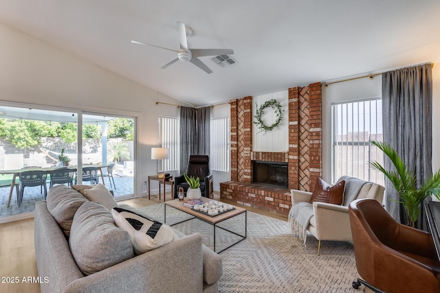 living room with ceiling fan, vaulted ceiling, light wood-type flooring, and a fireplace