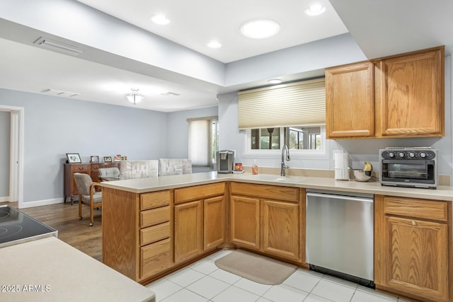 kitchen with stainless steel dishwasher, kitchen peninsula, sink, and range