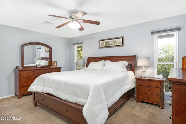 bedroom featuring light carpet, ceiling fan, and multiple windows