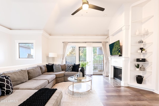 living room with a high end fireplace, vaulted ceiling, ceiling fan, crown molding, and wood-type flooring