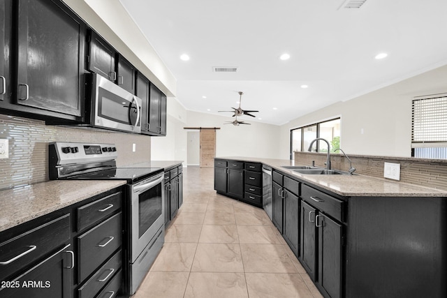 kitchen with lofted ceiling, stainless steel appliances, sink, backsplash, and a barn door