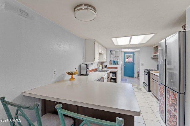 kitchen with sink, stainless steel fridge, range with gas stovetop, and light tile floors