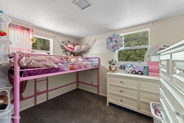 carpeted bedroom with a textured ceiling and multiple windows