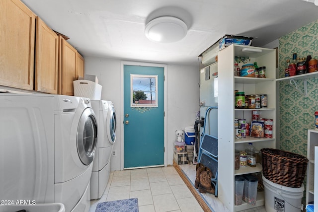 laundry area featuring washing machine and dryer, cabinets, and light tile floors