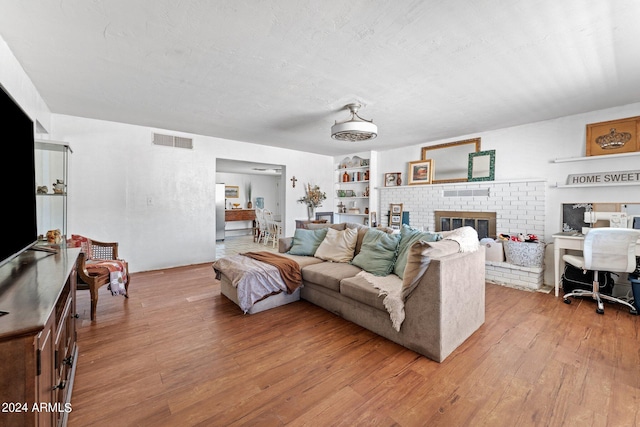 living room featuring a fireplace, built in shelves, and hardwood / wood-style floors