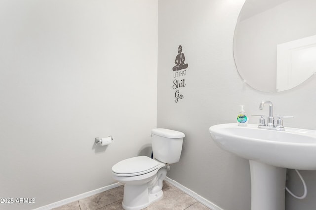 half bath featuring a sink, tile patterned flooring, toilet, and baseboards