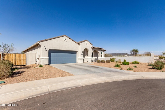 mediterranean / spanish-style house featuring an attached garage, fence, a tile roof, concrete driveway, and stucco siding