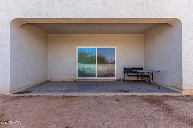 view of exterior entry featuring a patio area and stucco siding