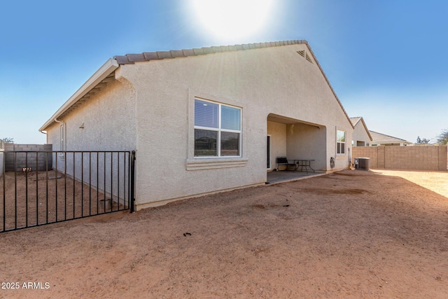 rear view of house with a patio area, a fenced backyard, cooling unit, and stucco siding