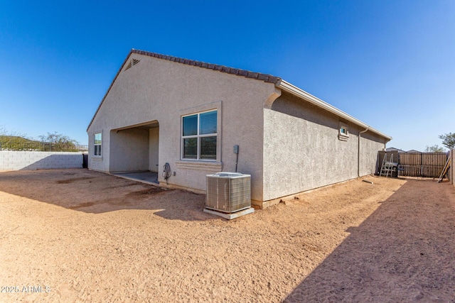 back of property with a fenced backyard, cooling unit, and stucco siding