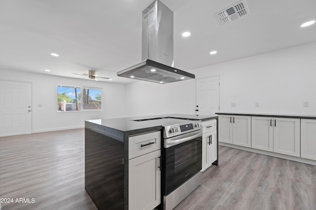 kitchen featuring ceiling fan, white cabinetry, island range hood, and stainless steel range with electric stovetop