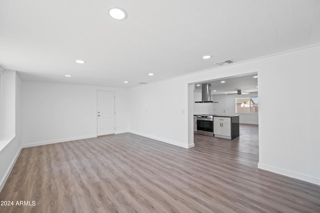 unfurnished living room featuring wood-type flooring and ornamental molding