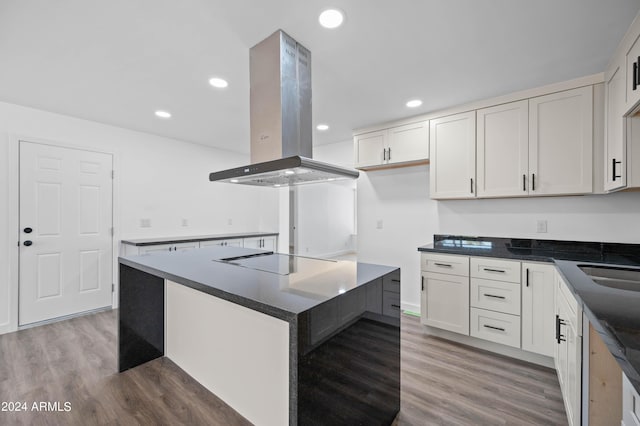 kitchen with black electric stovetop, a center island, dark wood-type flooring, white cabinets, and island range hood