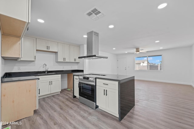 kitchen featuring island range hood, ceiling fan, stainless steel electric stove, light hardwood / wood-style flooring, and sink