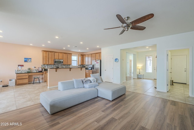 living area with light wood-type flooring, recessed lighting, and a ceiling fan