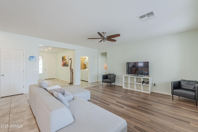 living area with light wood finished floors, baseboards, visible vents, and a ceiling fan