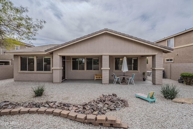 back of property with stucco siding, fence, and a patio area