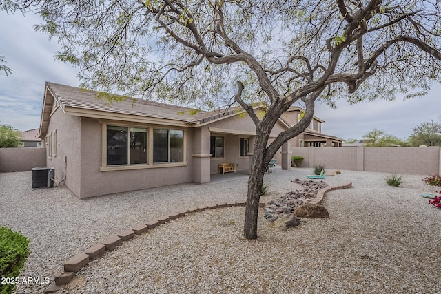 rear view of property with a fenced backyard, central AC unit, stucco siding, and a patio area