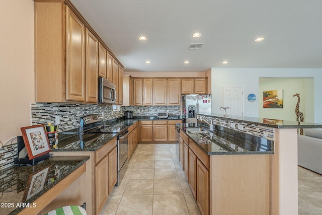 kitchen with visible vents, dark stone counters, appliances with stainless steel finishes, an island with sink, and light tile patterned floors