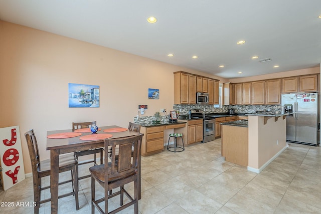 kitchen with visible vents, a kitchen island, tasteful backsplash, appliances with stainless steel finishes, and a breakfast bar area