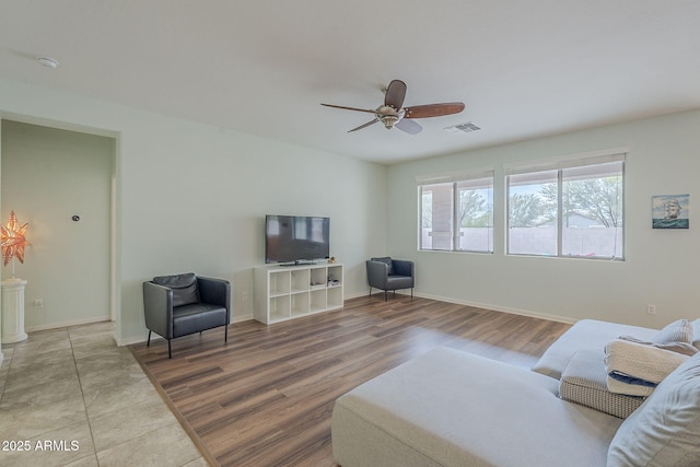 living area featuring baseboards, ceiling fan, visible vents, and light wood-type flooring