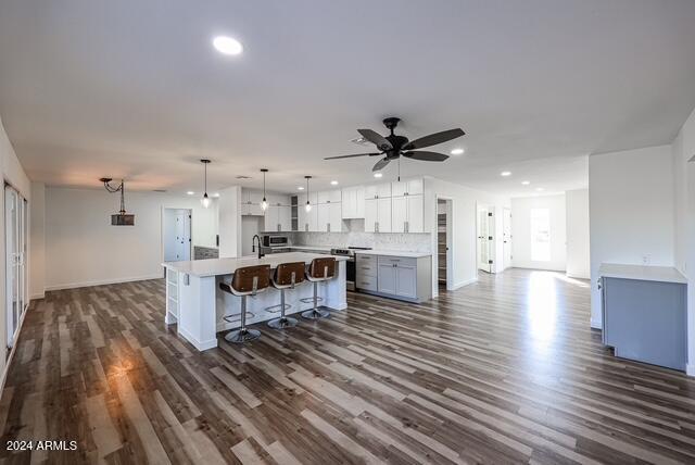 kitchen featuring ceiling fan, a center island, dark hardwood / wood-style floors, decorative light fixtures, and white cabinets