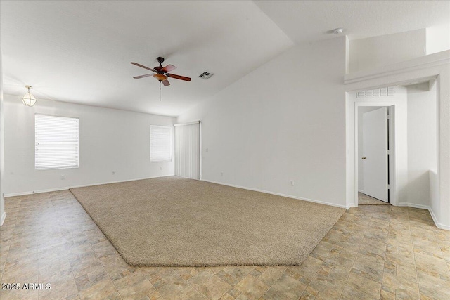 unfurnished room with a ceiling fan, baseboards, stone finish flooring, vaulted ceiling, and visible vents