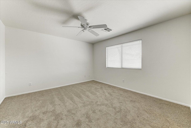 empty room with carpet flooring, ceiling fan, visible vents, and baseboards