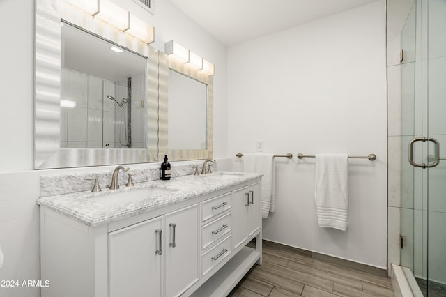 bathroom featuring wood-type flooring, a shower with door, and vanity