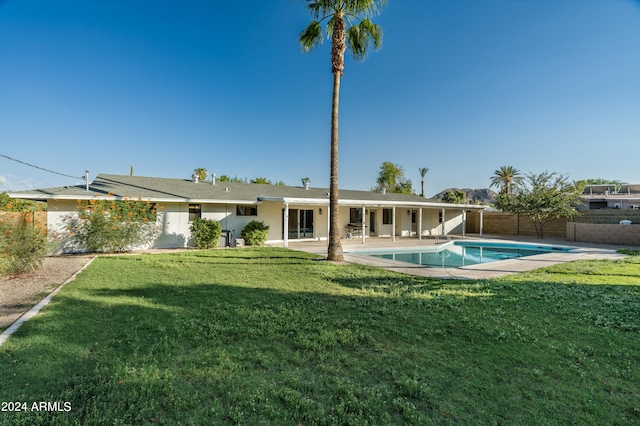 rear view of property with a yard, a fenced in pool, and a patio