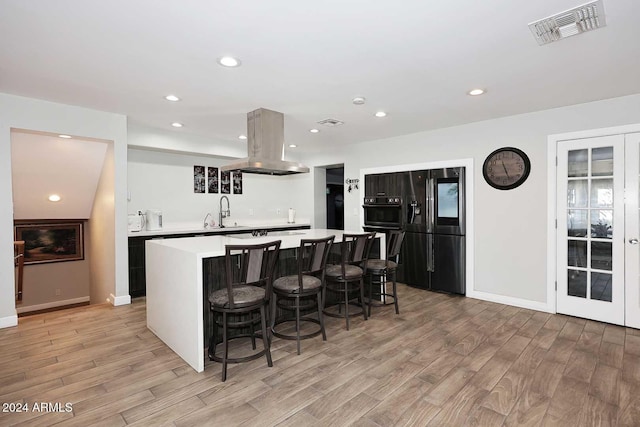 kitchen featuring a center island, sink, a breakfast bar area, black fridge with ice dispenser, and island exhaust hood