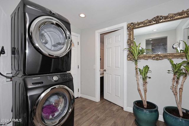 laundry room with dark hardwood / wood-style flooring and stacked washing maching and dryer