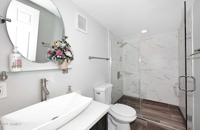 bathroom with vanity, toilet, and a shower with door