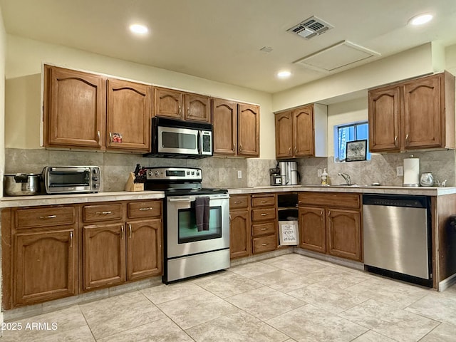 kitchen featuring appliances with stainless steel finishes, light countertops, visible vents, and decorative backsplash